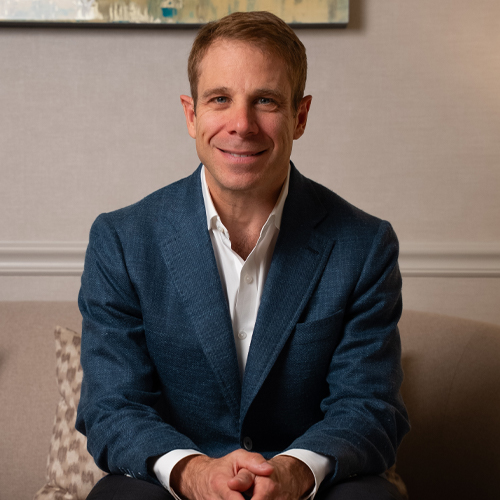 Dr. Jason Cooper sitting in a blue suit