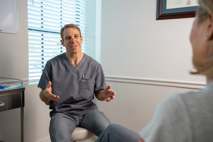 Dr. Jason Cooper speaking to female patient in treatment room