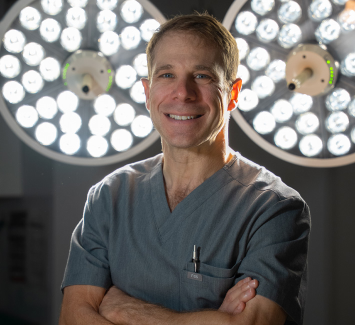 Dr. Jason Cooper in grey scubs in front of surgery lights